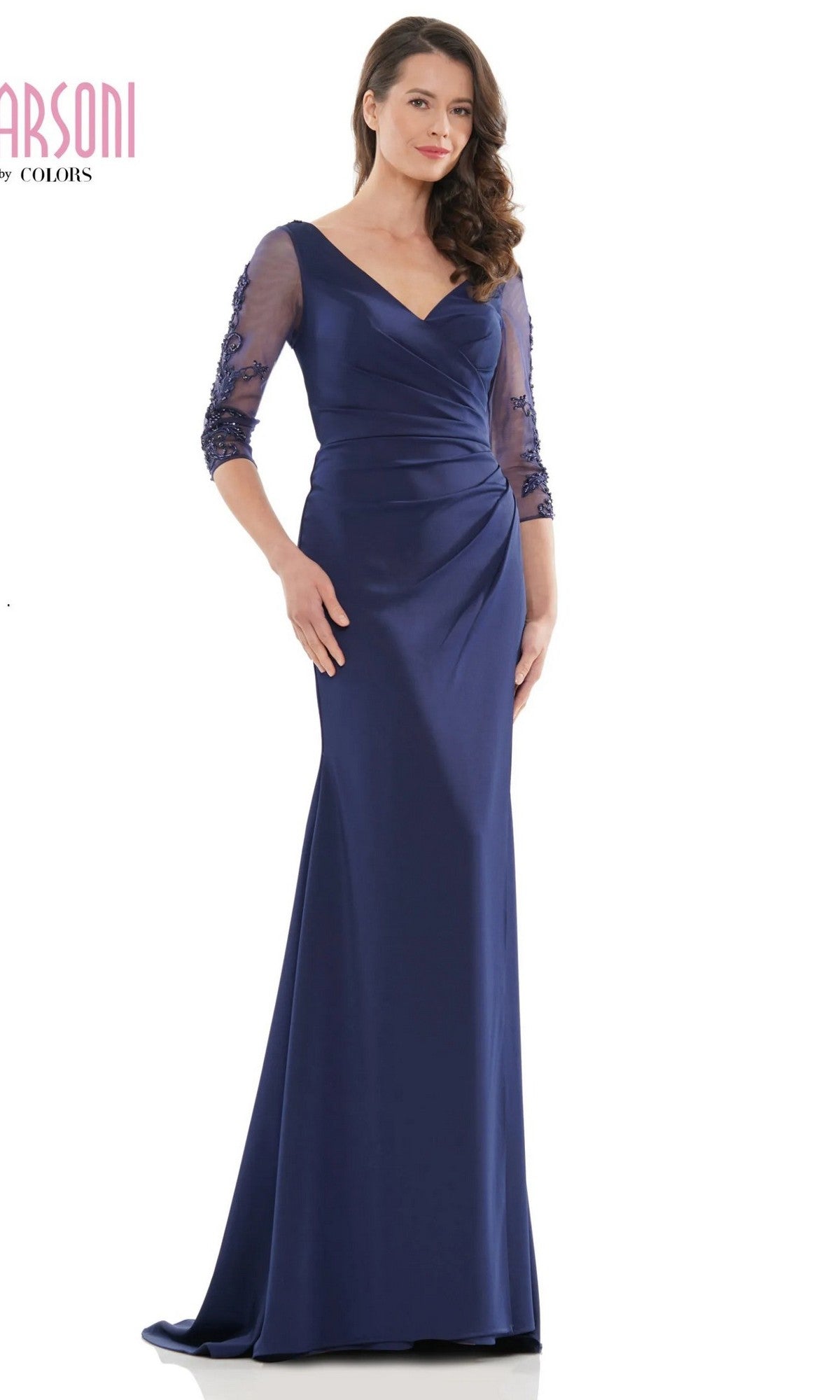 A woman models the Marsoni MV1146 long formal dress in navy, featuring a floor-length sheath skirt, three-quarter sheer sleeves, and elegant floral lace details, set against a white background.